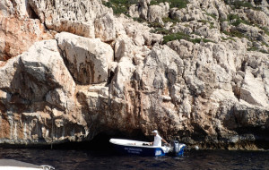 A boat on the exterior of the Blue Grotto with his passengers lying down ready to enter